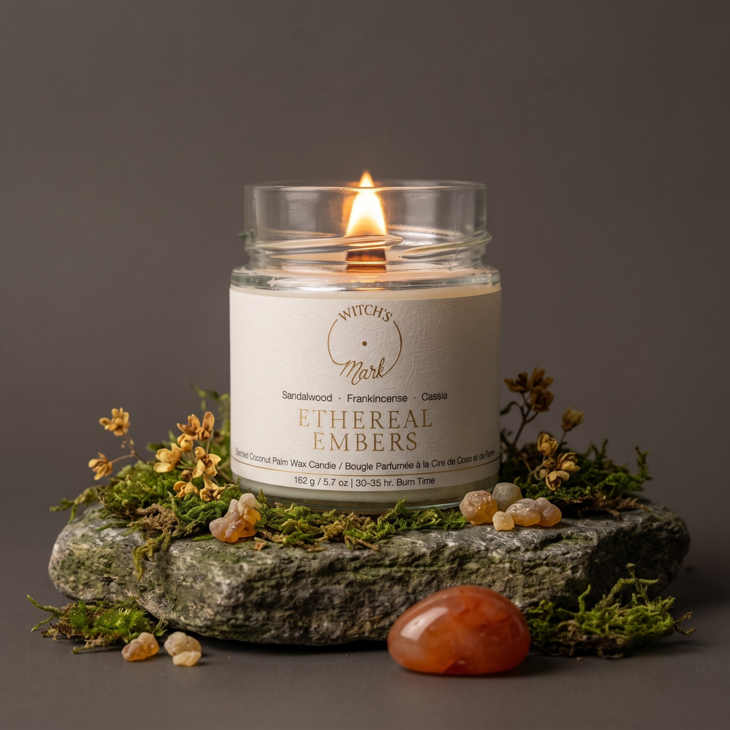 Ethereal Embers crystal candle on a bed of moss with cassia flower, frankincense tears, and a carnelian crystal.