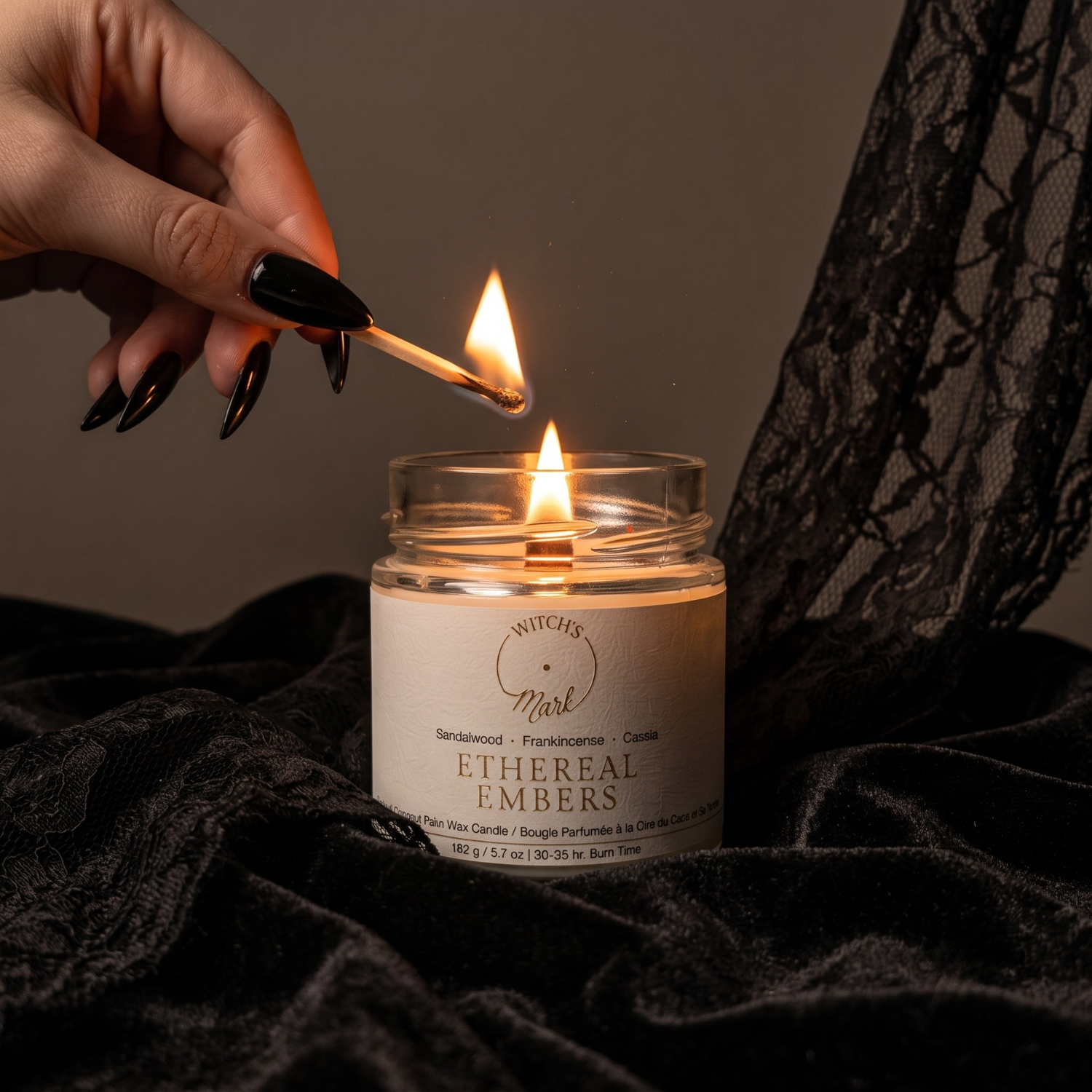Ethereal Embers crystal candle on black fabric being lit with a match